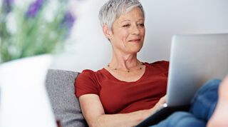 Mittelalte Frau mit kurzen grauen Haaren arbeitet am Laptop