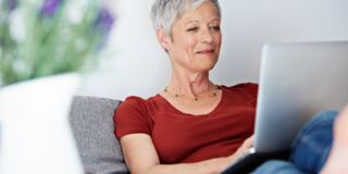 Mittelalte Frau mit kurzen grauen Haaren arbeitet am Laptop