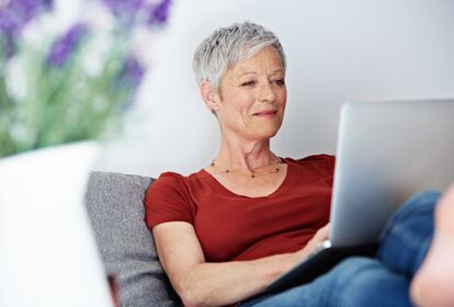 Mittelalte Frau mit kurzen grauen Haaren arbeitet am Laptop