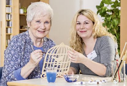 Ältere Frau und weibliche Pflegekraft basteln gemeinsam
