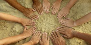 12 Hände mit unterschiedlichen Hautfarben Formen einen Kreis im Sand