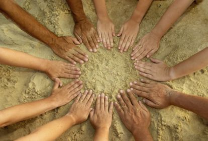 12 Hände mit unterschiedlichen Hautfarben Formen einen Kreis im Sand